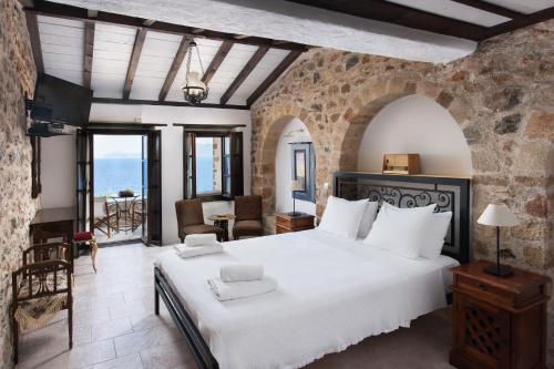 1 dormitorio con 1 cama blanca grande en una pared de piedra en Pablito House, en Monemvasia