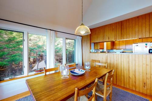 a kitchen with a wooden table with chairs and windows at Driftwood in Glenmere