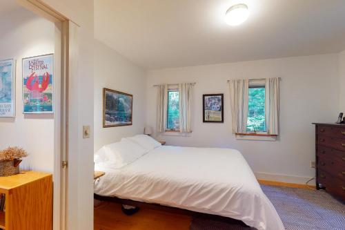 a bedroom with a white bed and two windows at Driftwood in Glenmere