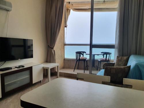 a living room with a flat screen tv and a table at Sea View Deluxe in Bat Yam