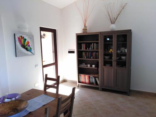 a dining room with a table and a book shelf at Villa panoramica immersa nel verde in Porto Pino