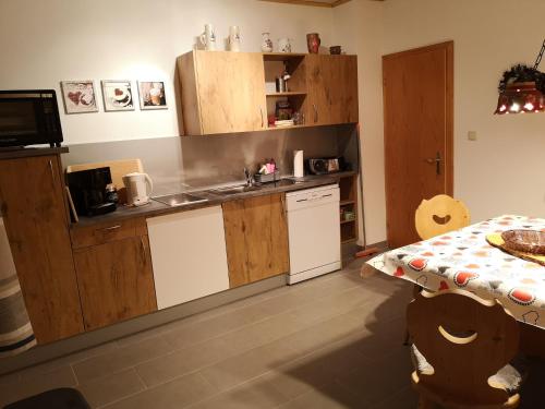 a kitchen with wooden cabinets and a sink and a table at Ferienwohnung - Haus Monika in Philippsreut
