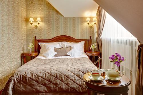 a bedroom with a bed and two tables with cups at Hotel Atlas Deluxe in Lviv