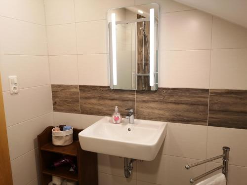 uma casa de banho com um lavatório branco e um espelho. em Ferienwohnung - Haus Monika em Philippsreut