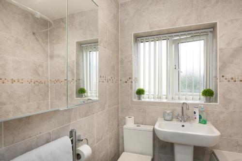 Un baño con lavabo, inodoro y espejo. en Nottingham Top Serviced Home - Chayil Experts, en Nottingham