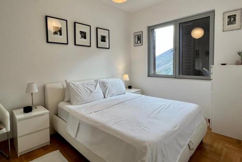 a white bedroom with a white bed and a window at Lavender Bay Apartment C23 in Kotor