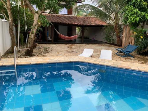 una piscina con 2 sillas y una hamaca junto a una casa en Almas gêmeas quarto casal en Angra dos Reis