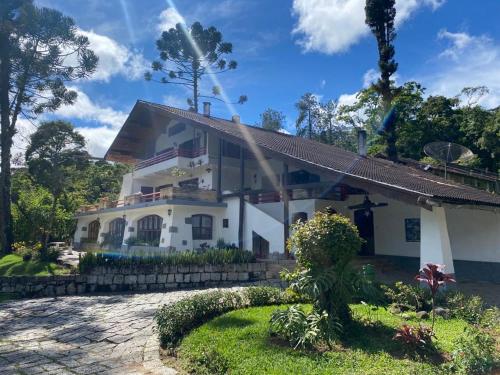a white house with a garden in front of it at Hotel Casa Alpina in Núcleo Mauá