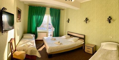 ボルィースピリにあるGolden Lion Hotelのベッド2台、緑のカーテン付きの窓が備わる客室です。