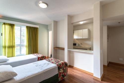 a hotel room with two beds and a kitchen at Eko Residence Hotel - próximo a Santa Casa e Auditório Araujo Vianna in Porto Alegre