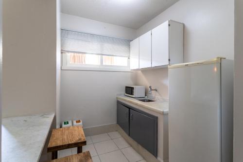 a small kitchen with white cabinets and a refrigerator at Eko Residence Hotel - próximo a Santa Casa e Auditório Araujo Vianna in Porto Alegre