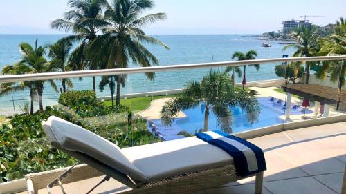 a white couch sitting on a balcony overlooking the ocean at Beachfront Condo in Bucearías in Bucerías