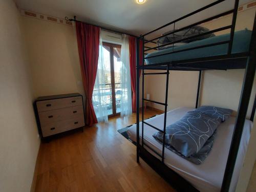 een slaapkamer met 2 stapelbedden, een dressoir en een raam bij Au cœur de St Jorioz, spacieux appartement avec terrasse et vue montagne. in Saint-Jorioz