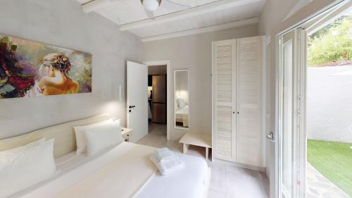 Yalos luxury home في Agii Saranta: غرفة نوم بسرير ابيض ولوحة على الحائط