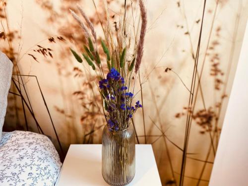 a vase with purple flowers sitting on a table at Résidence Adam à part in Valenciennes