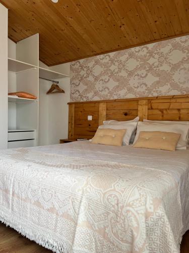 a bedroom with a large white bed with a wooden ceiling at Forno House - O Lagar in Vila Praia de Âncora
