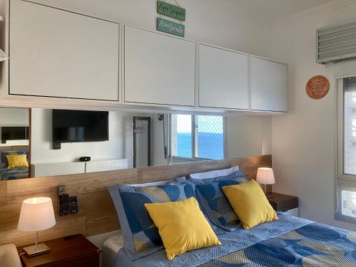 a bedroom with a bed with white cabinets and yellow pillows at Guarujá La Plage Pitangueiras in Guarujá