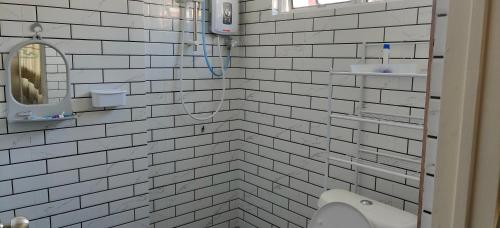 Baño de azulejos blancos con lavabo y espejo en Nenda’s Home, en Port Dickson