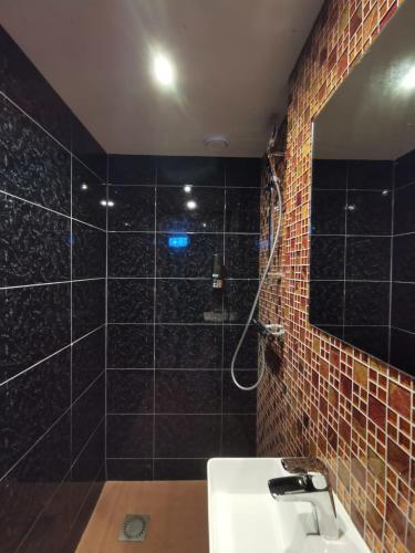 a bathroom with a sink and a shower with black tiles at Hotel Jesse in Amsterdam
