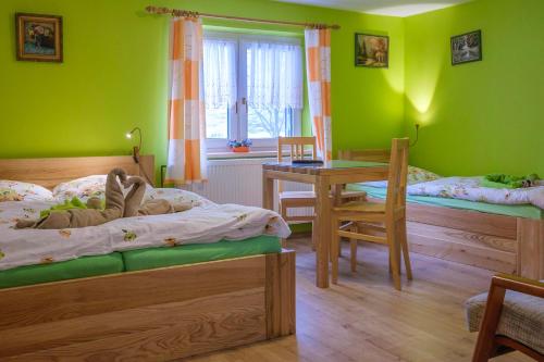 een slaapkamer met groene muren en 2 bedden en een tafel bij Hotel Kačenka in Králíky