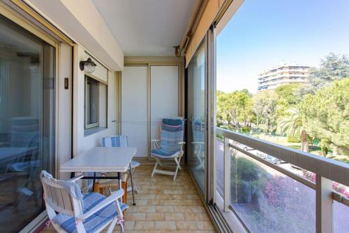 uma varanda com uma mesa e cadeiras e uma janela em Charming Apartment in The City Center With Furnished Terrace pool & Garage em Cagnes-sur-Mer