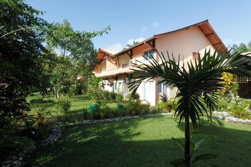 uma casa com uma palmeira em frente a um quintal em Hotel La Chaumiere em Matoury