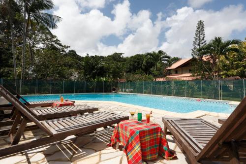 a swimming pool with a table and chairs next to it at Hotel La Chaumiere in Matoury