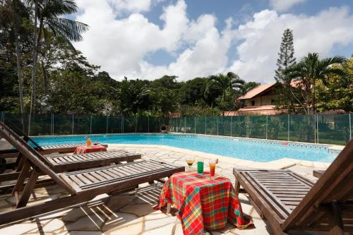een zwembad met een tafel en stoelen ernaast bij Hotel La Chaumiere in Matoury