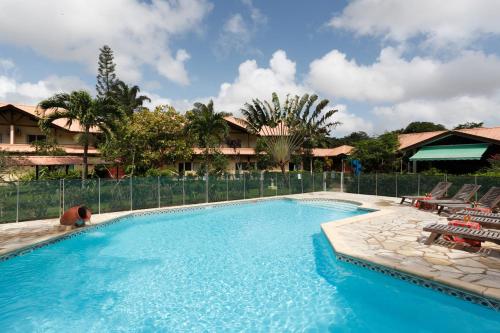 a swimming pool with chairs and a fence at Hotel La Chaumiere in Matoury