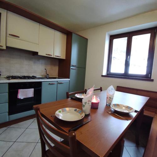 a kitchen with a wooden table with chairs and a tableablish at Orobie Holiday Apartments in Albosaggia