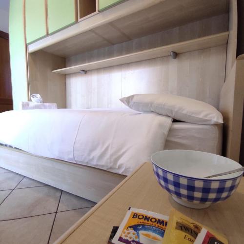 a bed with white sheets and a bowl on a table at Orobie Holiday Apartments in Albosaggia