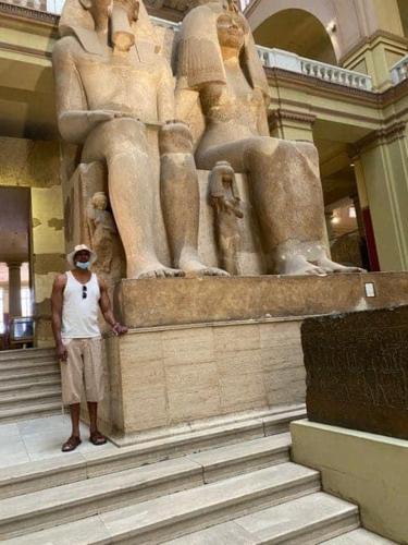 a man standing in front of a statue in a building at One Love Guesthouse & Restaurant in Luxor
