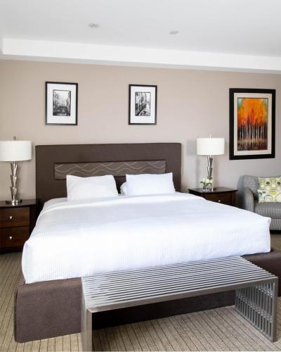 a bedroom with a large white bed and a chair at Retro Suites Hotel in Chatham