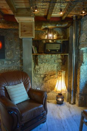 a living room with a leather chair and a lamp at Casa do Ti Gabriel in Sabugueiro