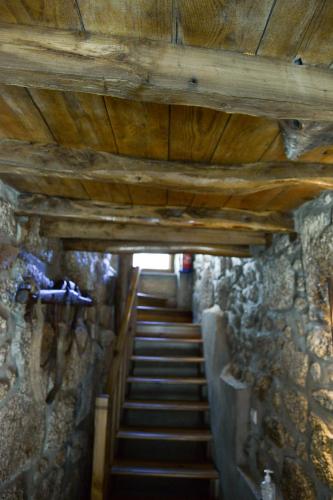 a staircase in a stone building with wooden ceilings at Casa do Ti Gabriel in Sabugueiro