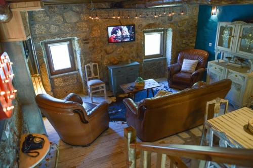 a living room with leather chairs and a tv at Casa do Ti Gabriel in Sabugueiro