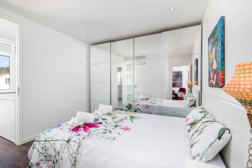 duża biała sypialnia z dużym lustrem w obiekcie Tilias Apartment at Estoril w mieście Estoril