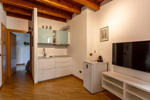 Una cocina con gabinetes blancos y un televisor de pantalla plana. en Appartamento Sant'Agostino, en Tirano