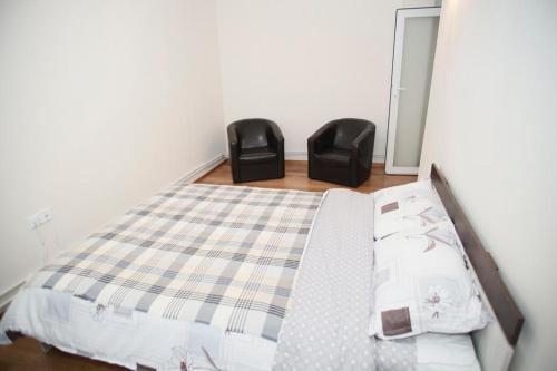福克沙尼的住宿－MiO Apartments，一间卧室配有一张床和两张黑色椅子