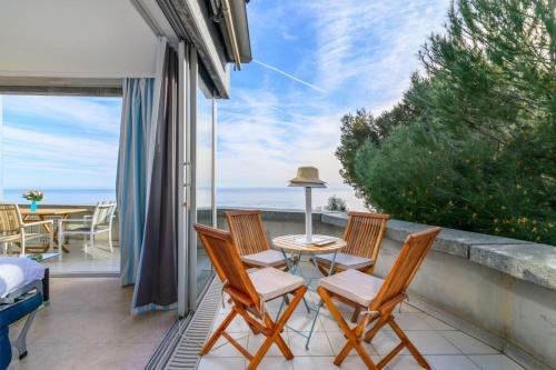 balcón con sillas, mesa y vistas al océano en Air-Conditioned Apartment With Sea View Furnished Terrace & Parking en Cap d'Ail