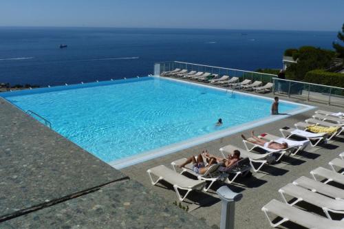 una piscina con personas sentadas en sillones en Air-Conditioned Apartment With Sea View Furnished Terrace & Parking en Cap d'Ail