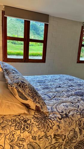 a bed in a bedroom with two windows at Finca Turística de Alojamiento Rural Avalon in Jardin