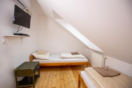 a attic room with two beds and a tv at NOBLE'S Panzió és Étterem in Nemesnép