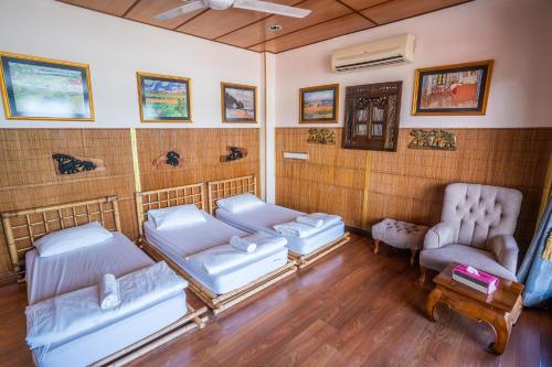 a room with two beds and two chairs in it at Lost Paradise Resort in Batu Ferringhi