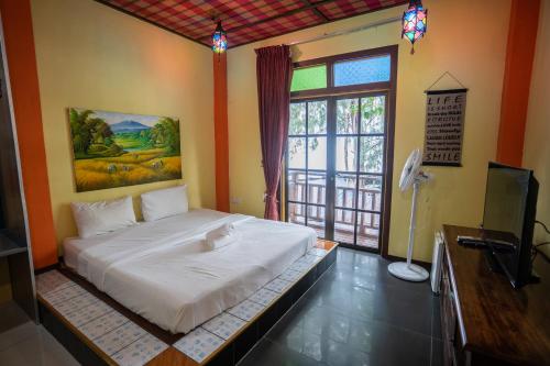 a bedroom with a bed and a tv and a window at Lost Paradise Resort in Batu Ferringhi
