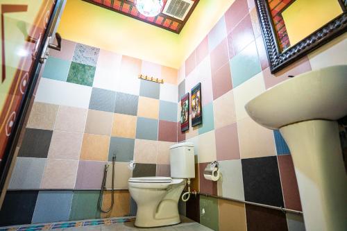 a bathroom with a toilet and a mirror and a sink at Lost Paradise Resort in Batu Ferringhi