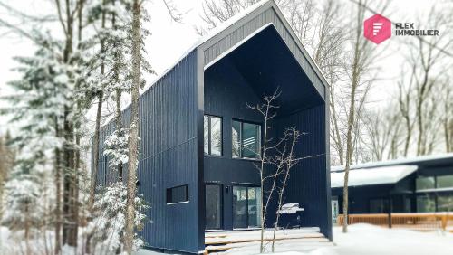 a black house in the snow with a stop sign at La Fleur Urbaine de Portneuf : 2.5 bathrooms, Hot tub, Sauna and Pool in Pont-Rouge