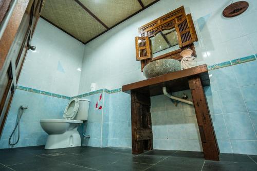a bathroom with a toilet and a wooden shelf at Lost Paradise Resort in Batu Ferringhi