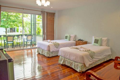 Habitación con 2 camas y balcón. en Menam Resort, en Nakhon Pathom