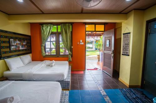 two beds in a room with orange walls at Lost Paradise Resort in Batu Ferringhi
